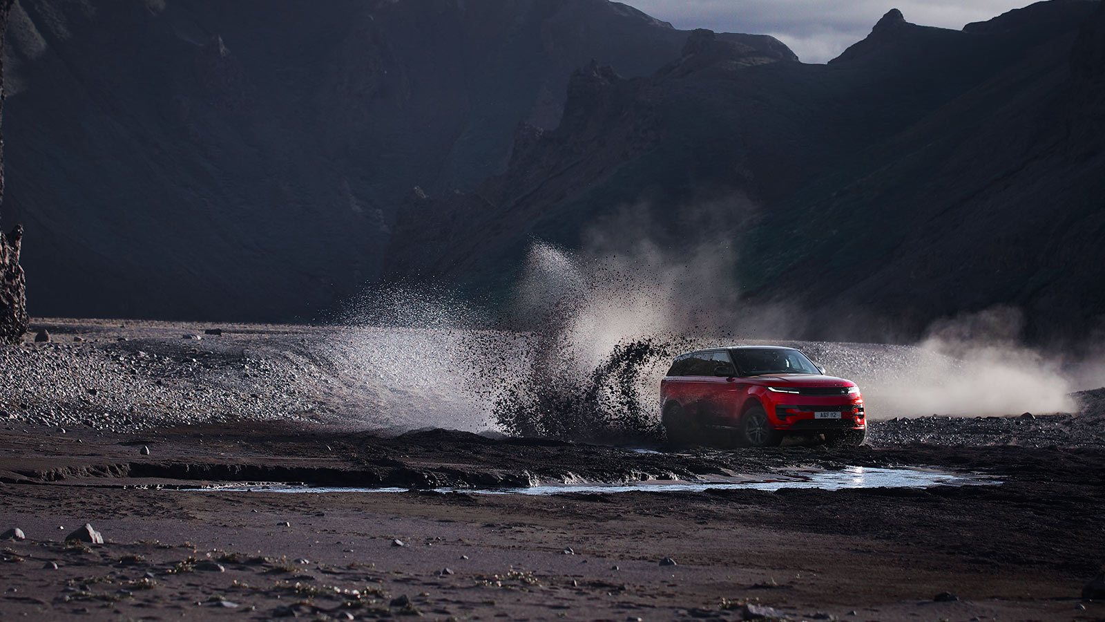 Red Range Rover driving through dust