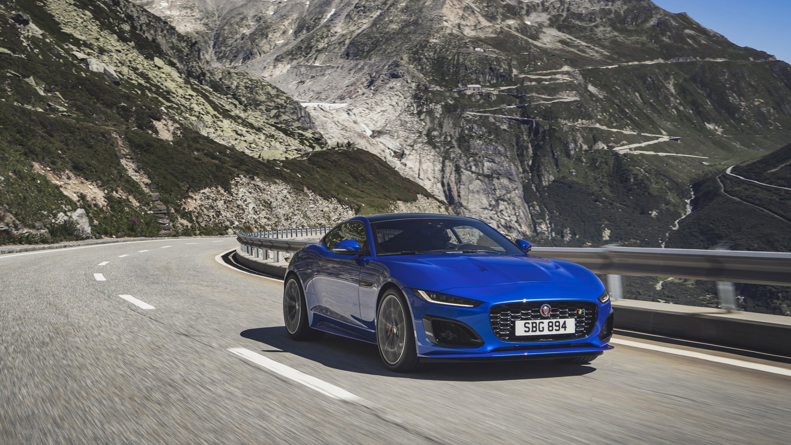 Blue Jaguar drives through mountains.